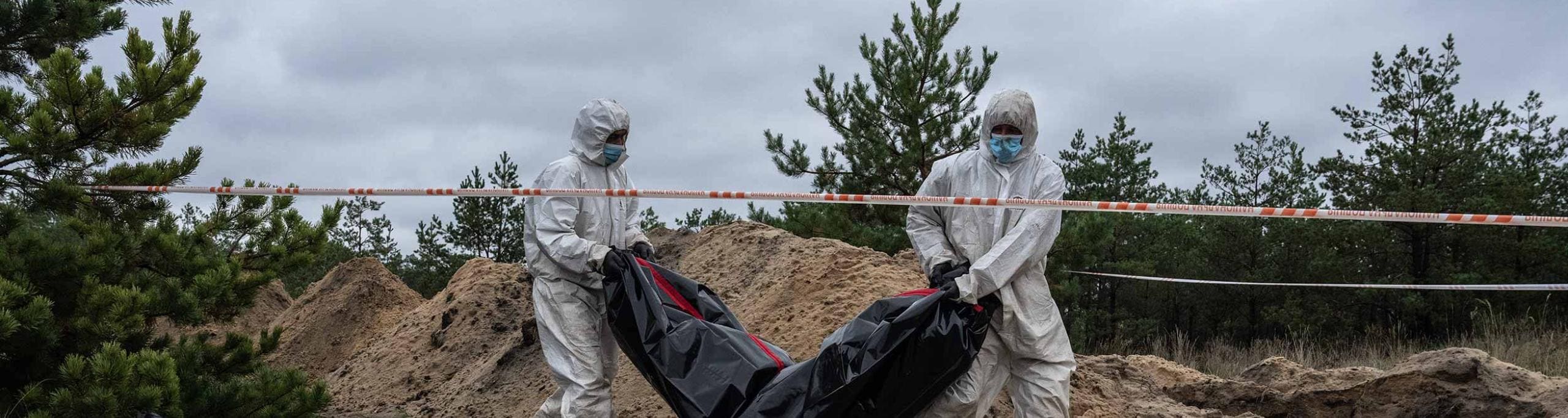 Forensic investigators remove an exhumed body from what is believed to be a mass grave on October 11, 2022 in Lyman, Donetsk oblast, Ukraine. Forensic investigators remove an exhumed body from what is believed to be a mass grave on October 11, 2022 in Lyman, Donetsk oblast, Ukraine.